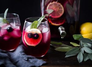 A glass of red wine with an orange slice and leaf.